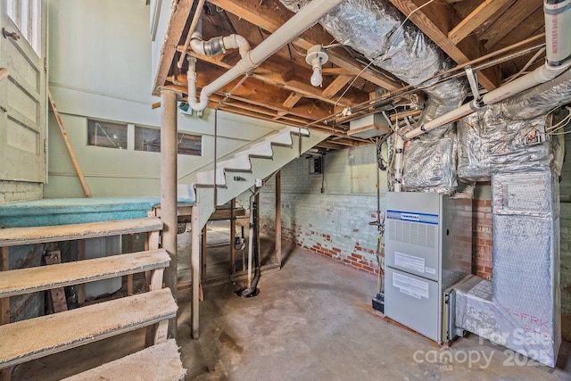 basement featuring brick wall and heating unit