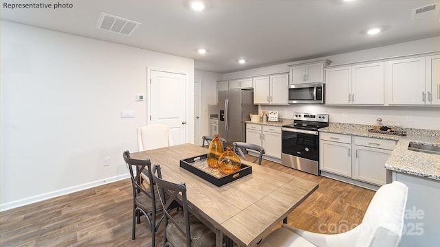 kitchen featuring light stone counters, appliances with stainless steel finishes, sink, and wood-type flooring