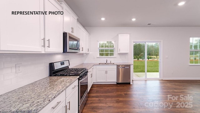 kitchen with sink, white cabinets, light stone counters, stainless steel appliances, and dark wood-type flooring