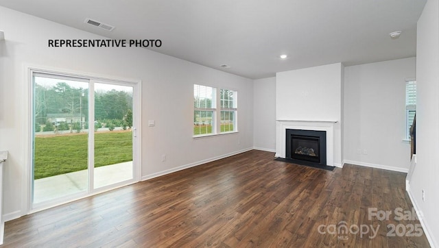 unfurnished living room with dark wood-type flooring and a healthy amount of sunlight