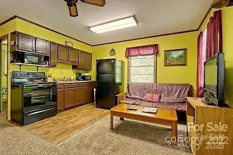 kitchen featuring black appliances, light wood-type flooring, crown molding, and ceiling fan