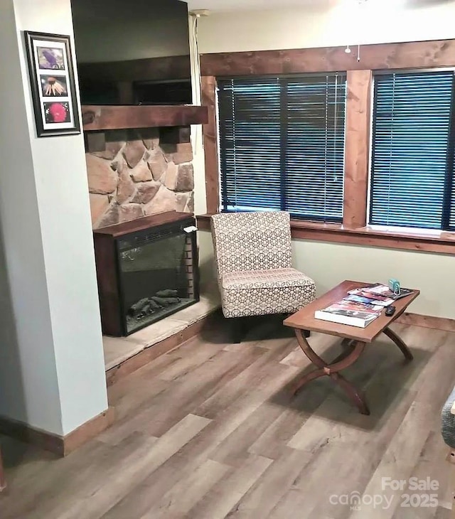 sitting room with hardwood / wood-style flooring and a stone fireplace