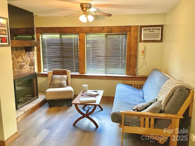 68 Vacation Dr, Whittier, NC 28789 - sitting room with a wall mounted AC, a fireplace, a ceiling fan, and wood finished floors