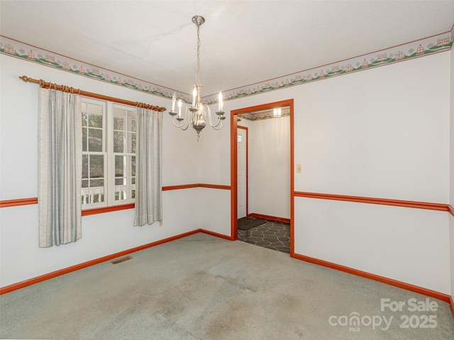 carpeted empty room featuring a notable chandelier