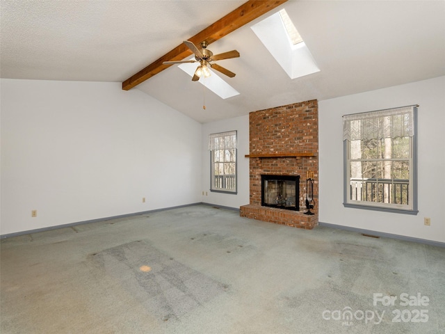 unfurnished living room featuring ceiling fan, vaulted ceiling with skylight, carpet, and a brick fireplace