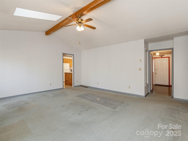 spare room featuring ceiling fan, vaulted ceiling with skylight, and light carpet