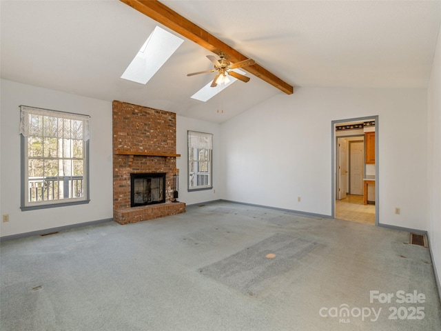 unfurnished living room featuring lofted ceiling with skylight, light carpet, ceiling fan, and a fireplace