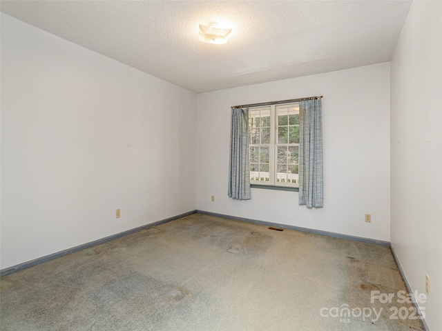 carpeted empty room featuring a textured ceiling