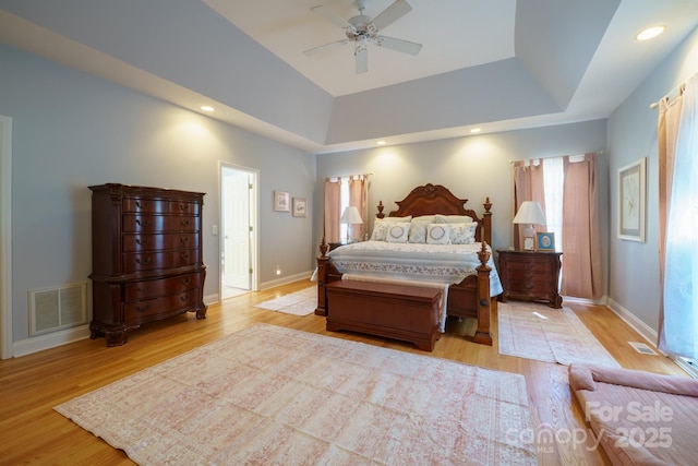 bedroom featuring ceiling fan, a tray ceiling, and light hardwood / wood-style flooring