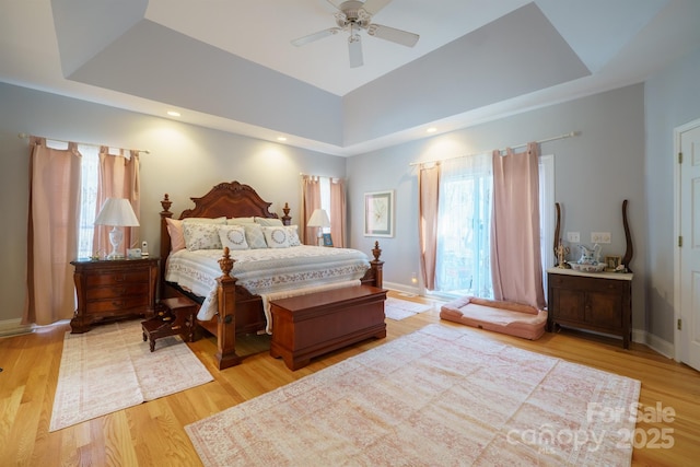 bedroom featuring a tray ceiling, ceiling fan, and light wood-type flooring