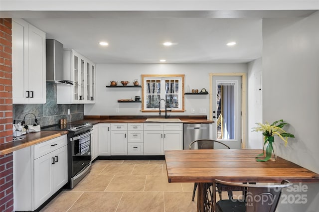 kitchen featuring wall chimney exhaust hood, sink, white cabinetry, tasteful backsplash, and stainless steel appliances