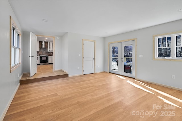 unfurnished living room featuring french doors and light hardwood / wood-style flooring