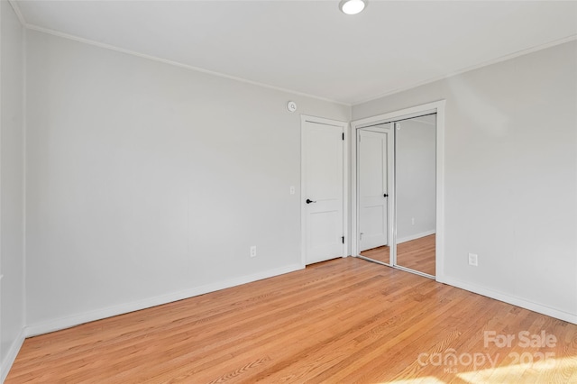 unfurnished bedroom with crown molding, a closet, and light wood-type flooring