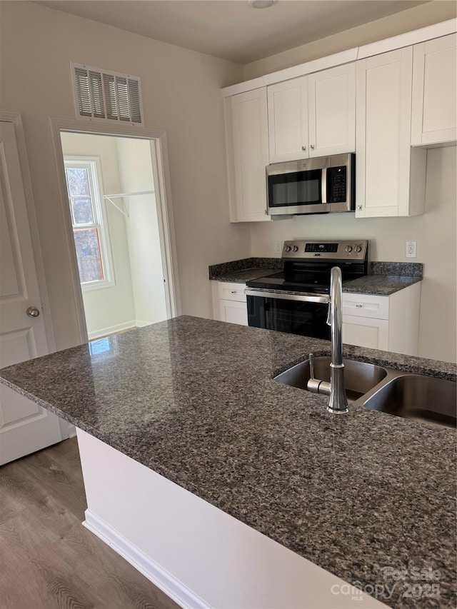 kitchen featuring stainless steel appliances, a sink, visible vents, and white cabinets