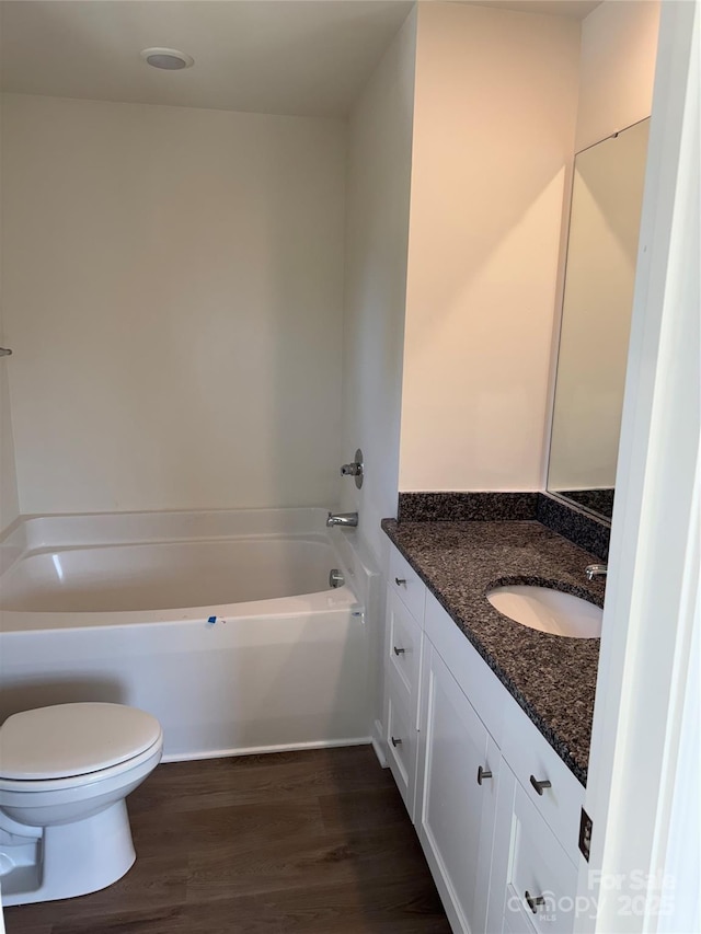 full bathroom featuring wood finished floors, vanity, toilet, and a bathing tub