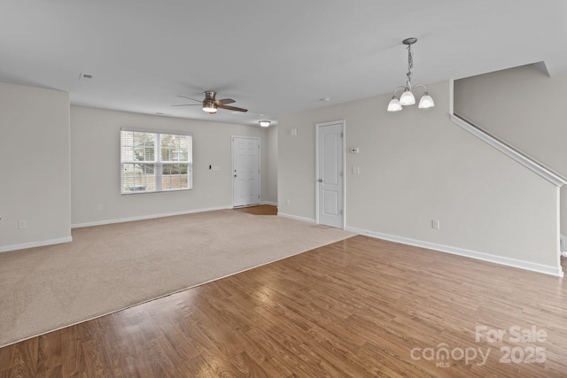 unfurnished living room featuring ceiling fan with notable chandelier and light hardwood / wood-style flooring