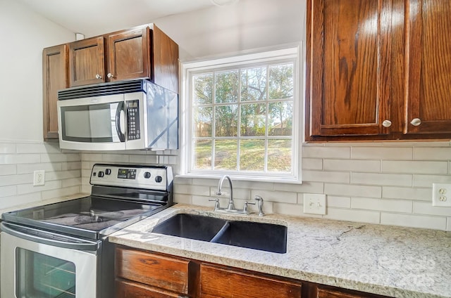 kitchen with light stone counters, sink, tasteful backsplash, and appliances with stainless steel finishes