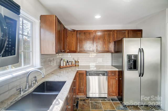 kitchen featuring sink, decorative backsplash, stainless steel appliances, and light stone countertops