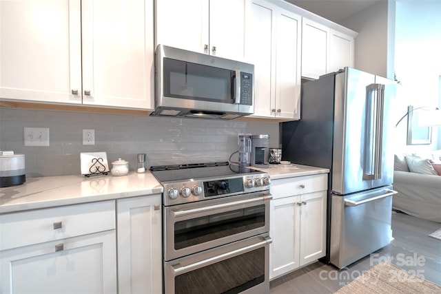 kitchen featuring tasteful backsplash, stainless steel appliances, light stone counters, and white cabinets