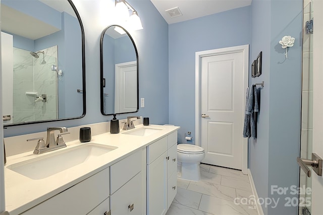 bathroom featuring a tile shower, vanity, and toilet