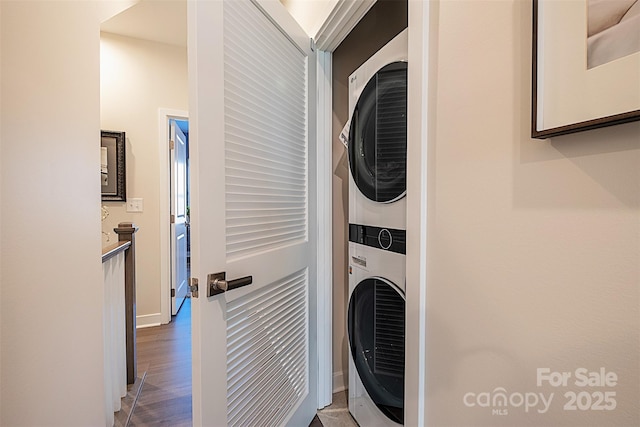 laundry room with stacked washing maching and dryer and dark hardwood / wood-style flooring