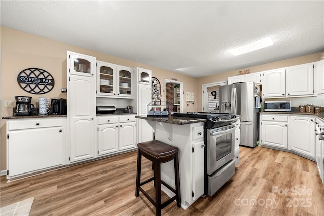 kitchen featuring a breakfast bar area, appliances with stainless steel finishes, a center island, white cabinets, and light wood-type flooring