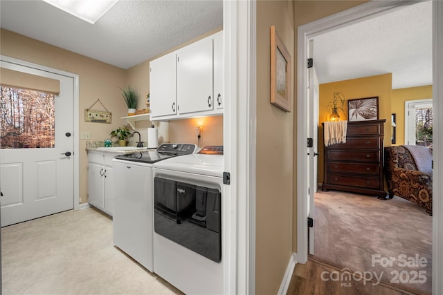 washroom featuring light carpet, a textured ceiling, cabinets, and washing machine and clothes dryer