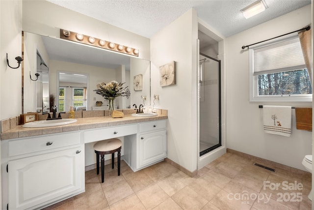 bathroom with vanity, a shower with door, and a textured ceiling