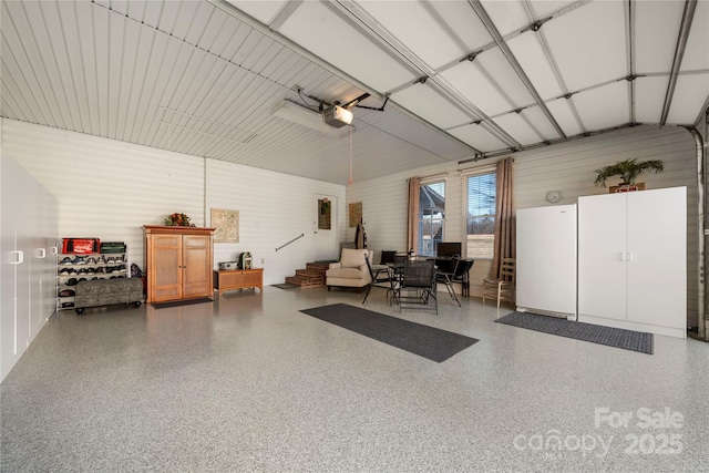 garage with a garage door opener and white fridge