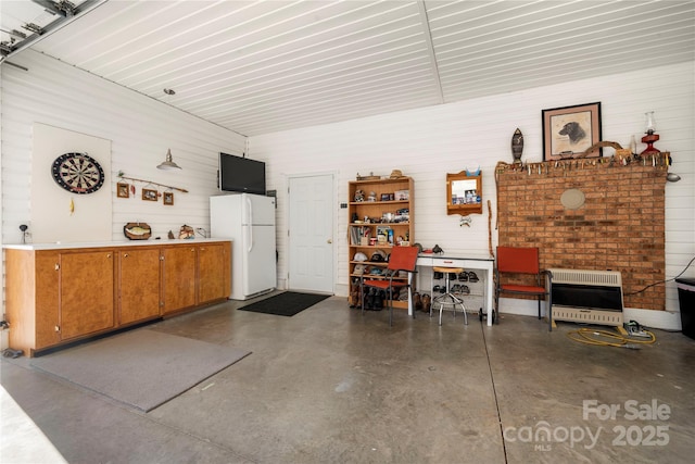 garage featuring heating unit and white fridge