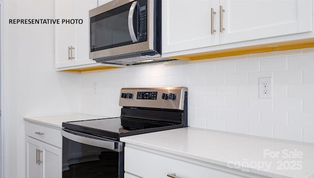 kitchen with backsplash, stainless steel appliances, and white cabinets