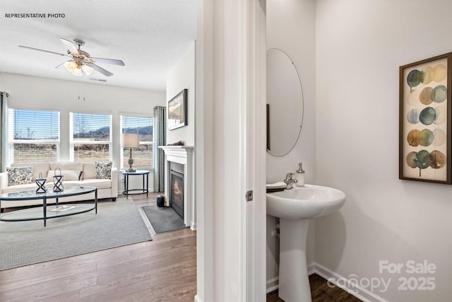 bathroom with ceiling fan, hardwood / wood-style flooring, sink, and a textured ceiling