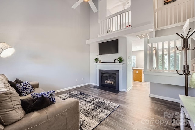 living room with a high ceiling, hardwood / wood-style floors, and ceiling fan