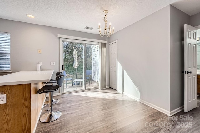 unfurnished office with an inviting chandelier, a textured ceiling, and light wood-type flooring