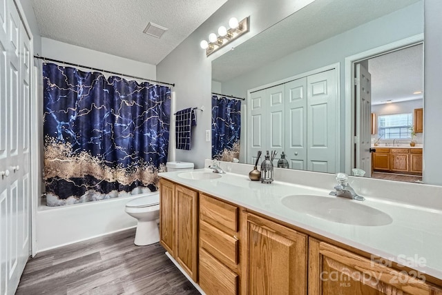 full bathroom with toilet, a textured ceiling, vanity, shower / bath combination with curtain, and hardwood / wood-style floors