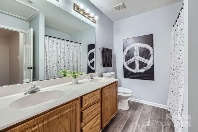 bathroom with hardwood / wood-style flooring, vanity, walk in shower, toilet, and a textured ceiling