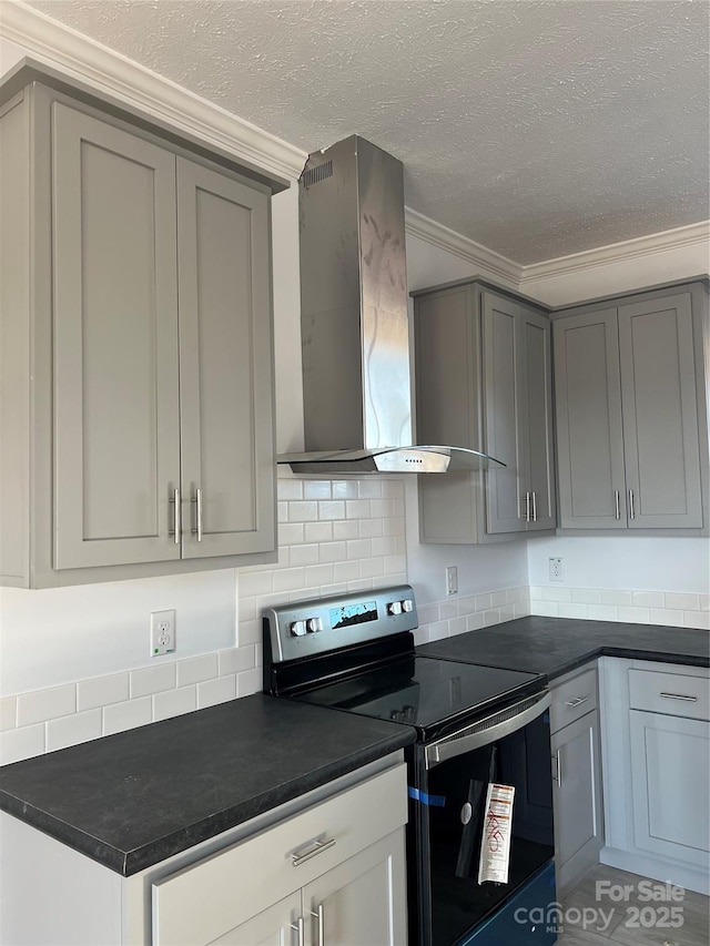 kitchen with crown molding, dark countertops, gray cabinets, stainless steel range with electric cooktop, and wall chimney exhaust hood