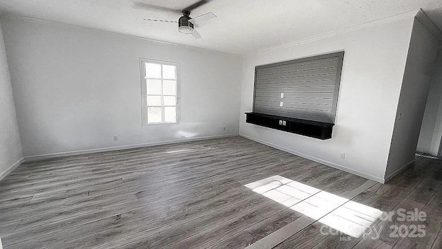 spare room with dark wood finished floors, a ceiling fan, ornamental molding, a textured ceiling, and baseboards