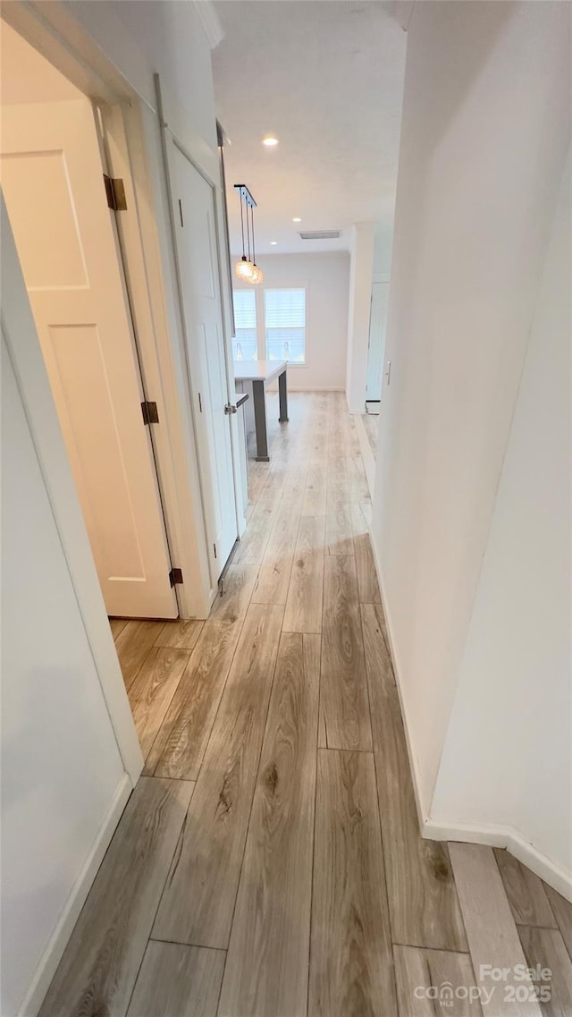 hallway featuring baseboards, recessed lighting, and light wood-style floors