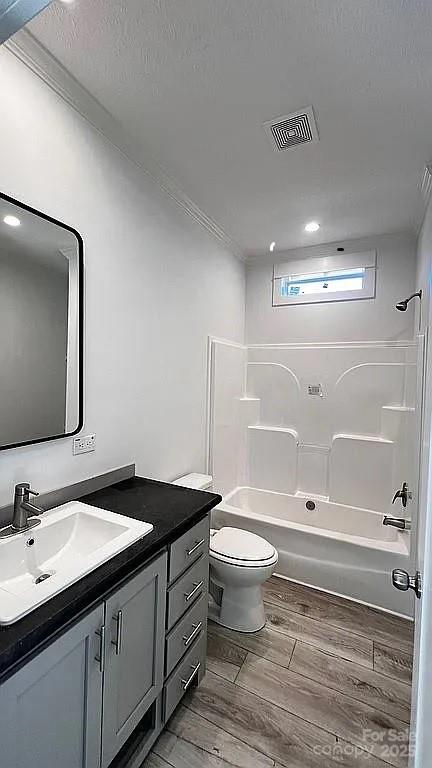 full bathroom featuring toilet, shower / bath combination, vanity, visible vents, and wood tiled floor