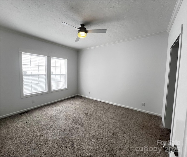 empty room featuring a textured ceiling, ornamental molding, dark carpet, and a ceiling fan