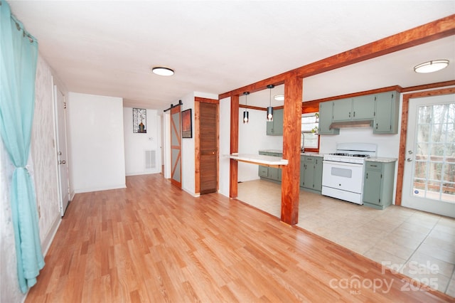 kitchen featuring a barn door, white range with gas cooktop, and light wood-type flooring