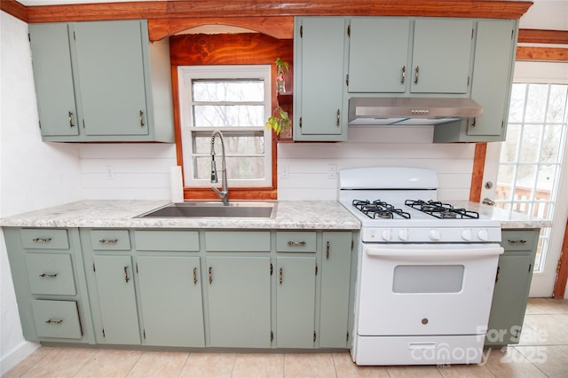 kitchen featuring ventilation hood, white range with gas cooktop, sink, and green cabinetry