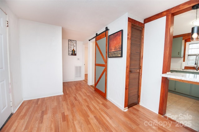 hallway featuring a barn door and light wood-type flooring