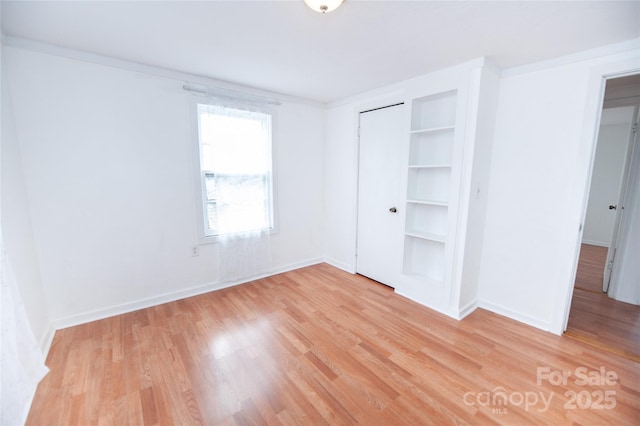 unfurnished bedroom featuring ornamental molding, a closet, and light wood-type flooring