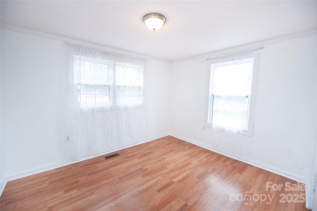 empty room with ornamental molding and light hardwood / wood-style floors