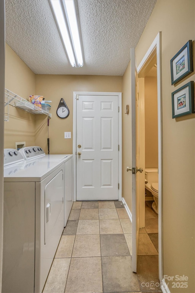 clothes washing area featuring light tile patterned flooring, washing machine and clothes dryer, and a textured ceiling