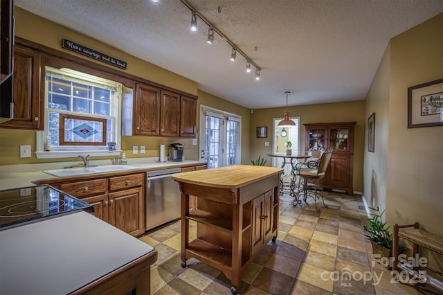 kitchen with sink, hanging light fixtures, a textured ceiling, stainless steel dishwasher, and french doors