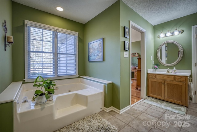 bathroom featuring tile patterned floors, vanity, a bath, and a textured ceiling