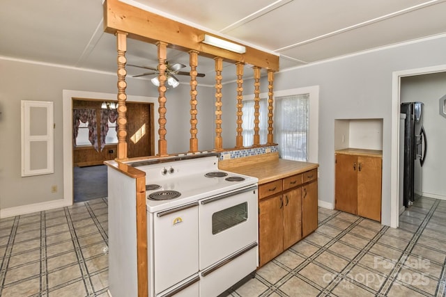 kitchen featuring brown cabinets, freestanding refrigerator, ceiling fan, double oven range, and baseboards